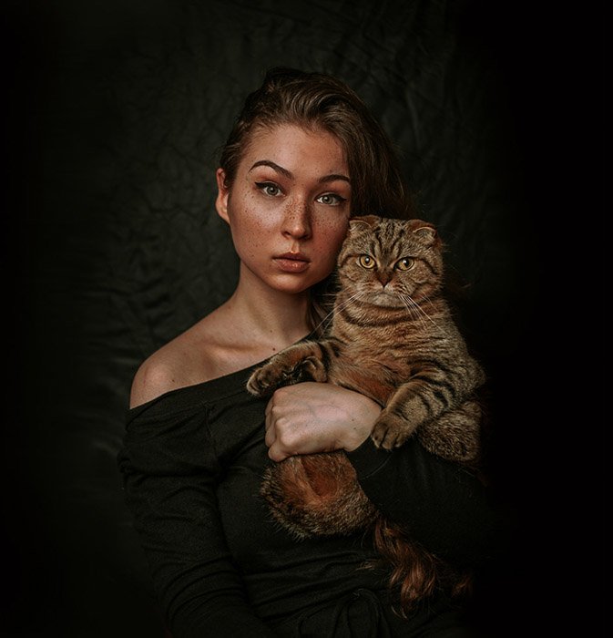 Атмосферный портрет женщины-модели, держащей коричневую кошку