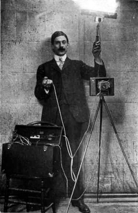 A black and white portrait of a photographer using early flash photography 