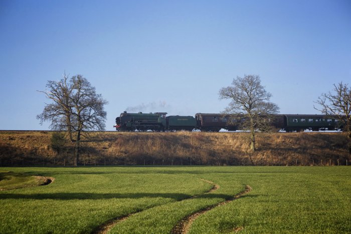 Паровозик едет по сочной зеленой сельской местности - железнодорожная фотография