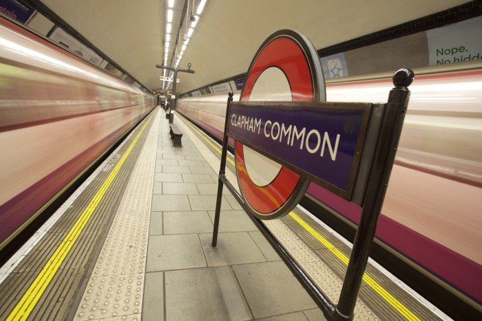 Знак лондонского метро между двумя движущимися поездами