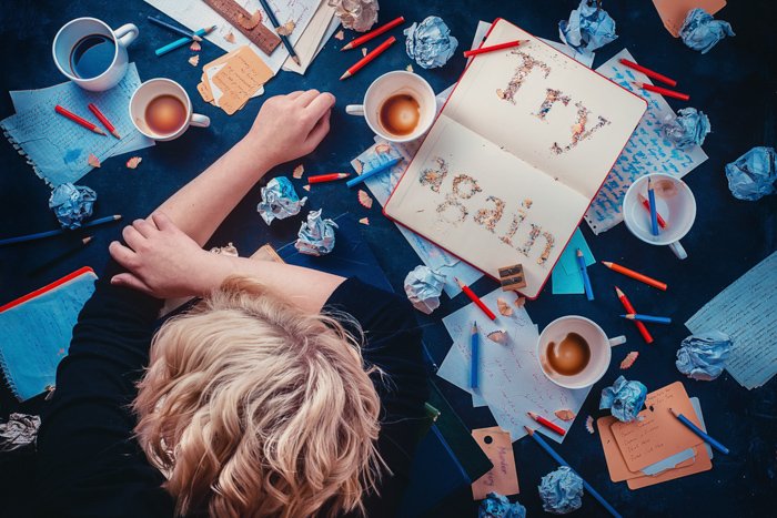 Фотография ребенка, опирающегося на стол, заставленный кофейными чашками и канцелярскими принадлежностями, на темном фоне - креативная композиция натюрморта