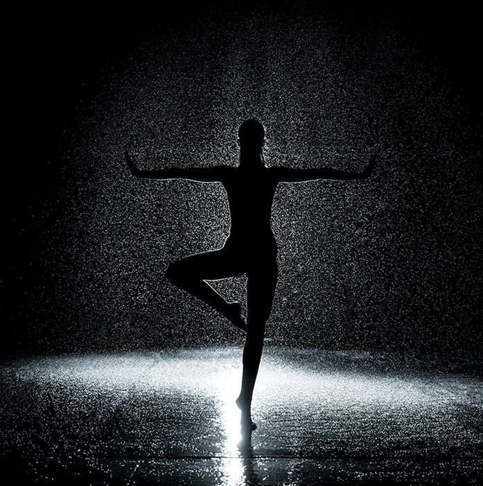 Художественная балетная фотография силуэта балерины, танцующей на сцене при слабом освещении