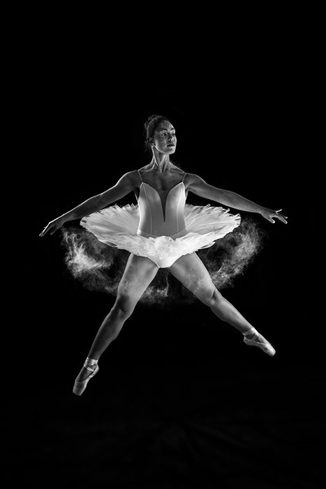 Художественная балетная фотография женщины-балерины, танцующей на сцене при слабом освещении