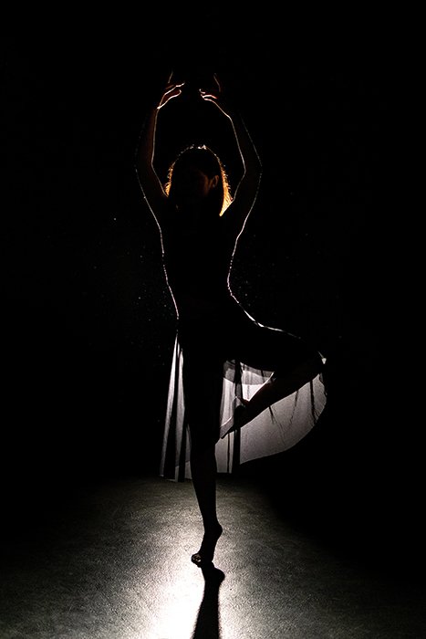 Красивая балетная фотография танцовщицы, позирующей на сцене при слабом освещении