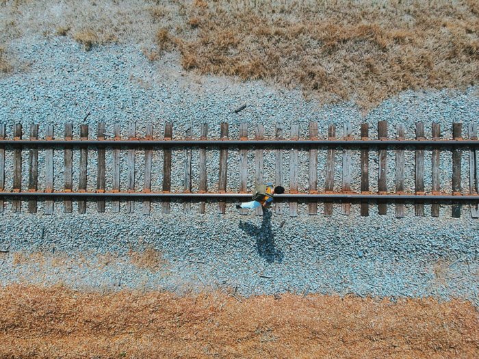 Угол обзора камеры с высоты птичьего полета человека, идущего по железнодорожным путям
