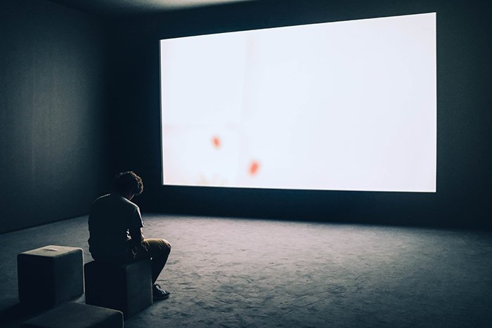 Концептуальный автопортрет мужчины, сидящего перед большим пустым экраном
