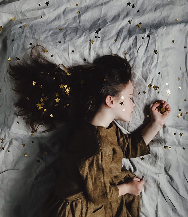 Мечтательный концептуальный портрет спящей маленькой девочки, усыпанной золотыми звездами