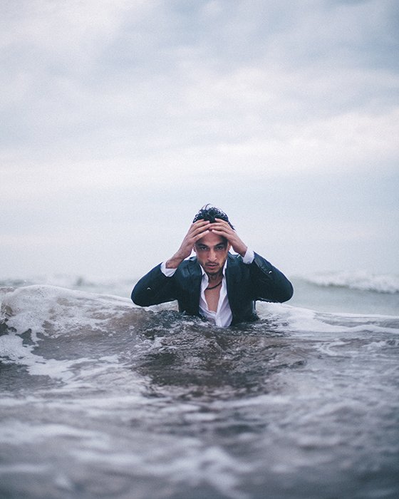 Драматический концептуальный портрет человека, выходящего из моря с руками на голове - идеи концептуальной фотографии
