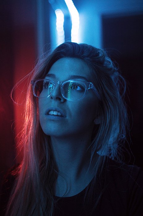 Атмосферный неоновый фотопортрет женщины-модели с неоновыми огнями, отражающимися в ее очках