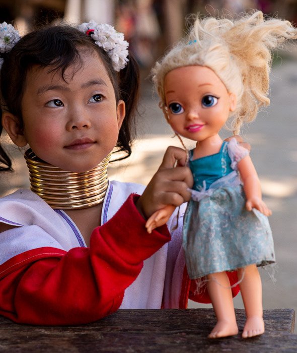 Молодая девочка Карен держит пластмассовую куклу