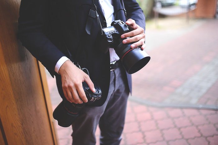 Крупный план профессионального фотографа, держащего зеркальный фотоаппарат на фотосессии