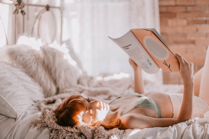 Будуарный портрет женщины, лежащей на кровати и читающей книгу