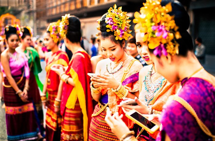 Уличный портрет девушек, проверяющих свои смартфоны перед началом ежегодного парада цветов в Чиангмае, Таиланд. Фотографии, которые рассказывают историю