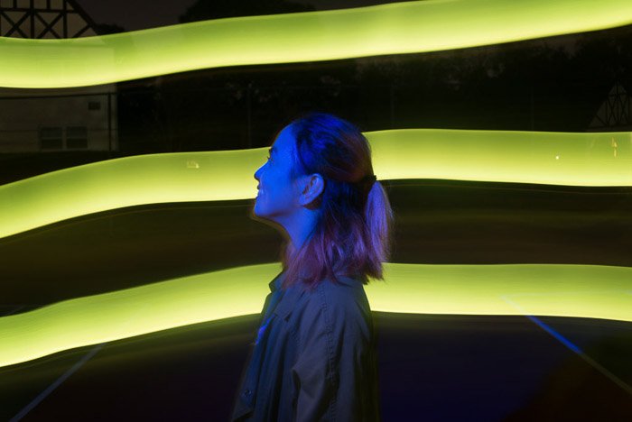 Портрет женщины-модели, позирующей на фоне неоновых зеленых полос света