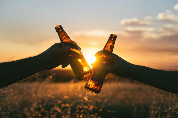 Пивная фотография на открытом воздухе двух людей с бутылками на закате