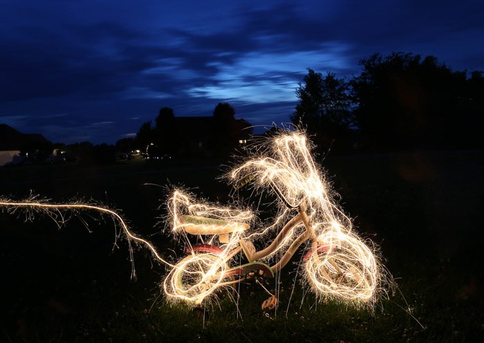 Велосипед в окружении световых картин, на улице ночью, снято с использованием светодиодных инструментов для рисования светом