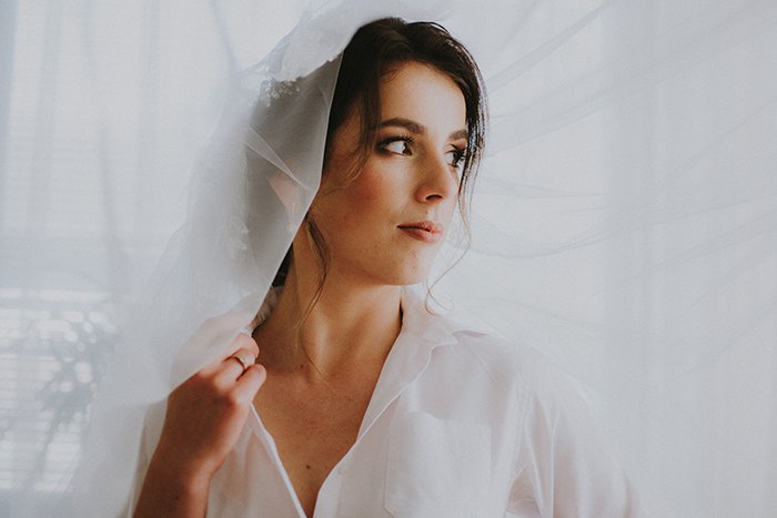 Dreamy portrait of the female model posing indoors with white veil
