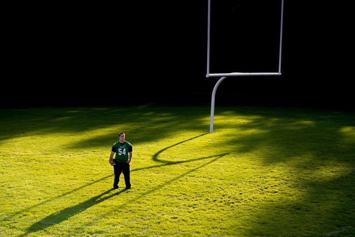 Спортсмен, стоящий на спортивной площадке при ярком свете - высококонтрастное освещение