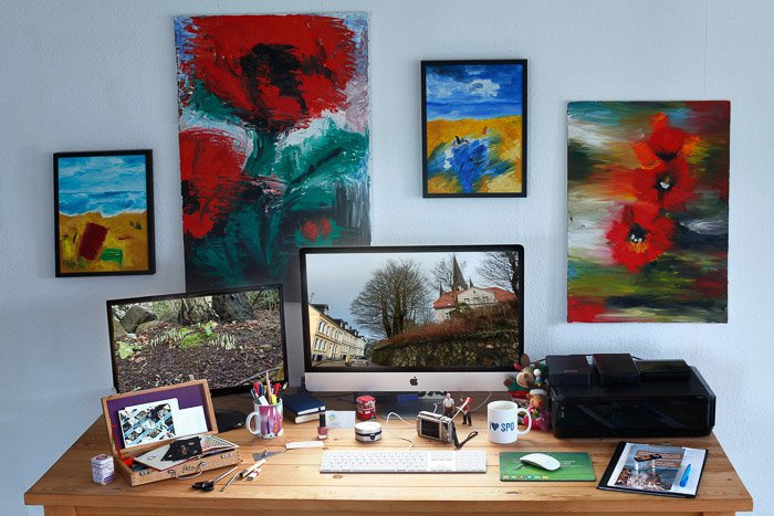 Письменный стол в домашнем офисе в окружении красочных картин - цветовой режим в фотошопе