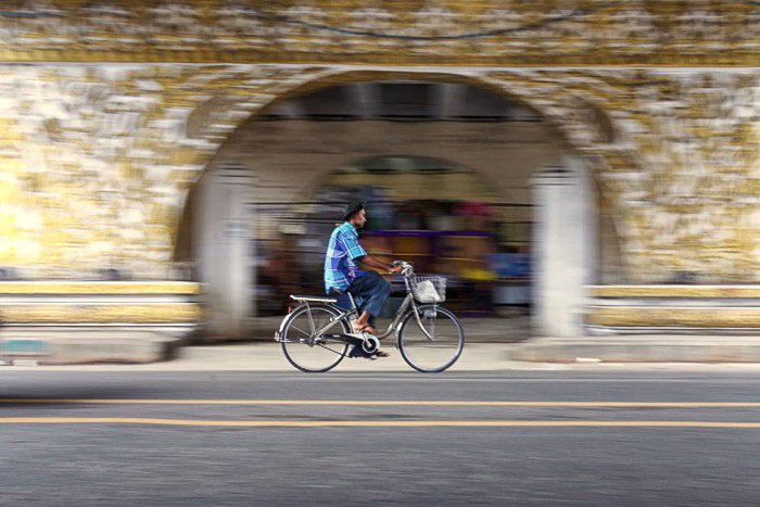 Велосипедист проезжает под мостом с творческим размытием движения с использованием длинной выдержки
