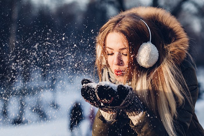 Close up winter portrait photography of female model posing playfully in falling snow