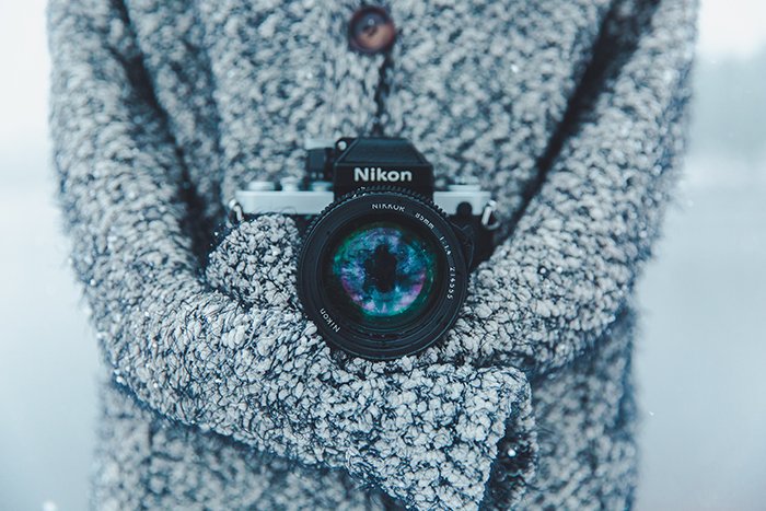 Крупный план камеры Nikon на шее фотографа, снимающего снежные портреты