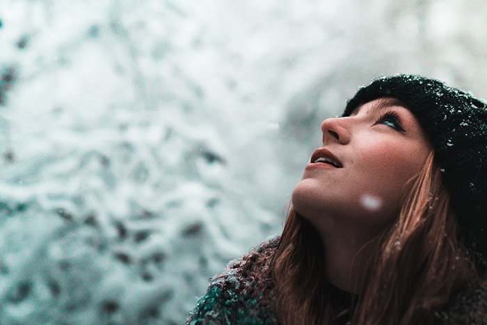 Крупный план зимней портретной фотографии женской модели, позирующей на падающем снегу