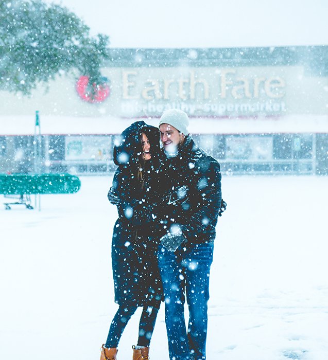Close up winter portrait photography of the couple posing in falling snow