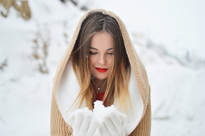 Close up winter portrait photography of the female model posing in falling snow