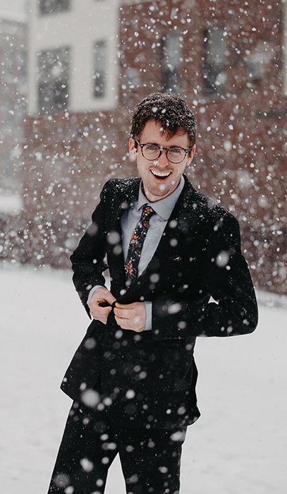 Веселый зимний портрет мужской модели, позирующей под падающим снегом