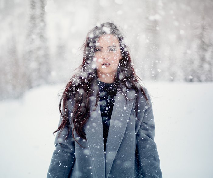 Волшебный зимний портретный фотоснимок женской модели, позирующей на падающем снегу