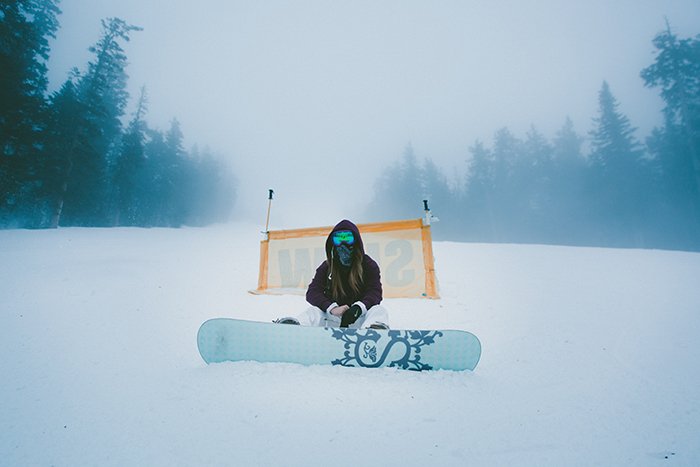 Атмосферные снежные портреты женщины-сноубордистки, позирующей на фоне зимнего пейзажа