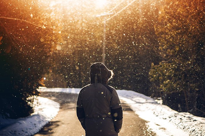 Атмосферный зимний портрет модели, идущей по дороге под падающим снегом
