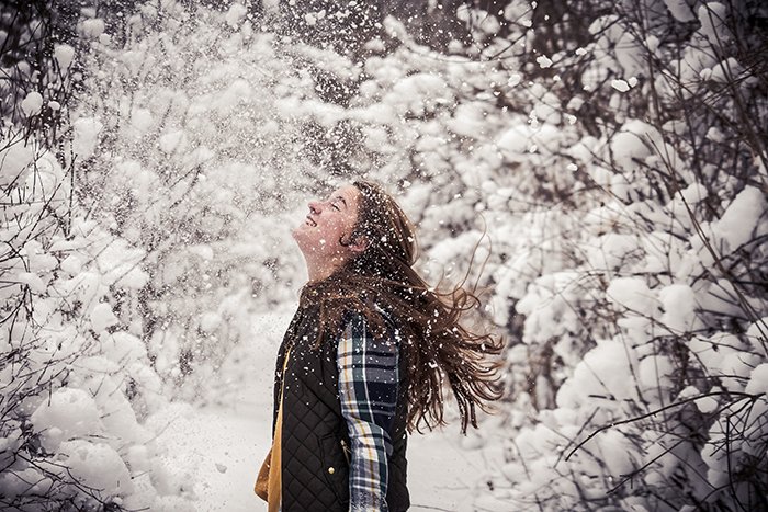 Веселый снежный портрет женской модели, смеющейся и играющей в снегу