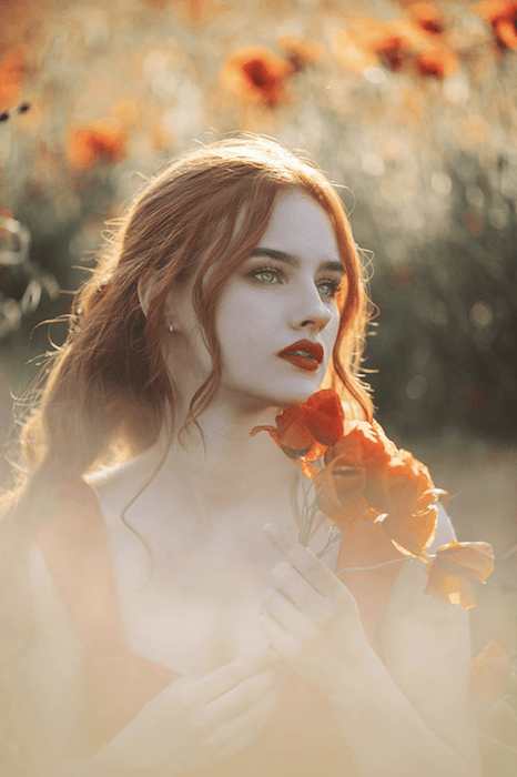 мечтательный портрет рыжеволосой модели в поле роз