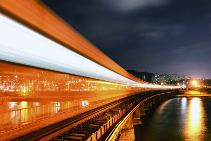 Красочные оранжевые и белые световые следы, движущиеся над железнодорожными путями