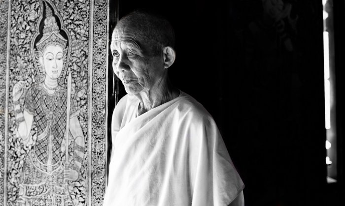 A black and white portarit of buddhist monk posing by window light