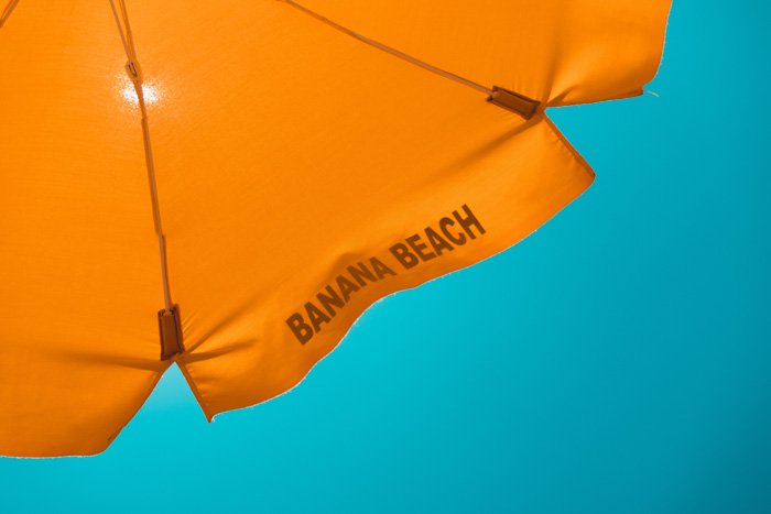 Оранжевый зонт сидит на фоне манящего голубого неба