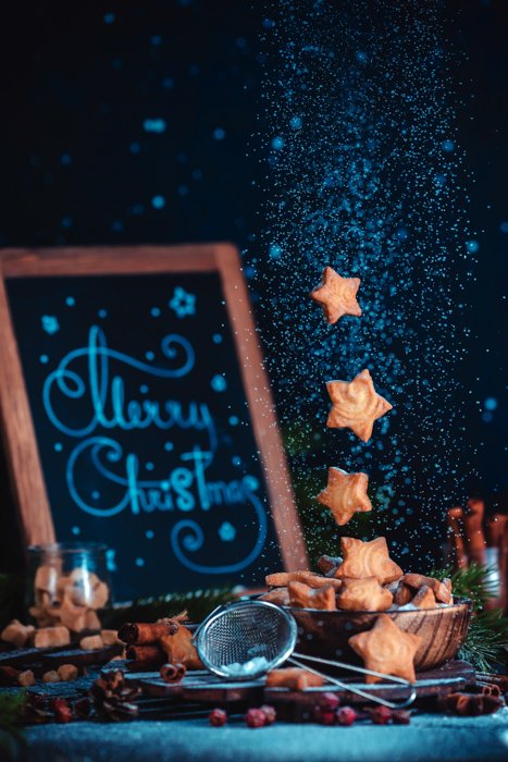 Рождественский тематический пищевой натюрморт, включающий кофейные чашки, формочки для печенья, сахар и печенье