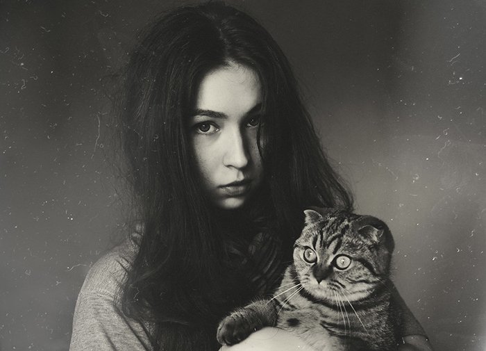 A film noir inspired grainy portrait of girl holding a cat