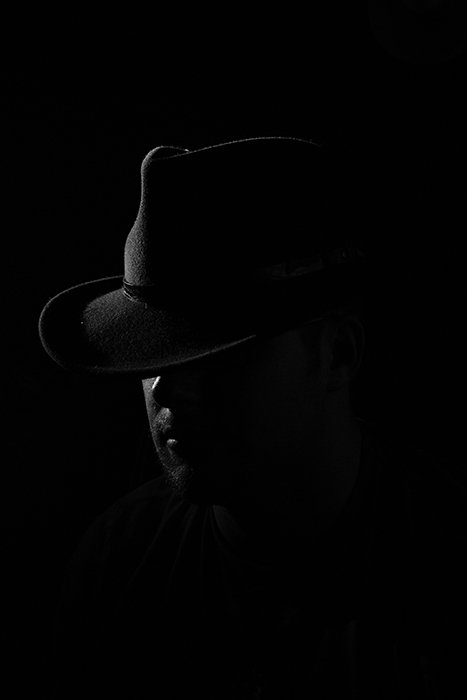 Film noir photography portrait of the male model wearing a cowboy hat