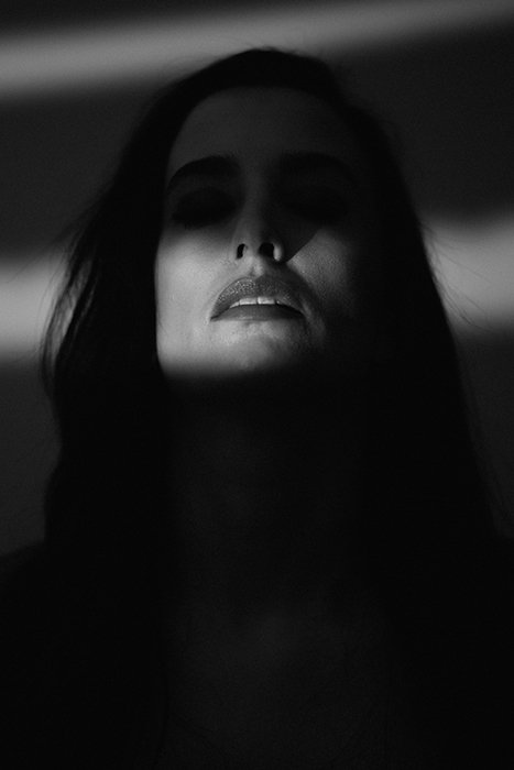 Портрет женщины-модели, чьи глаза естественно скрыты темными тенями для создания жуткой и интригующей атмосферы.