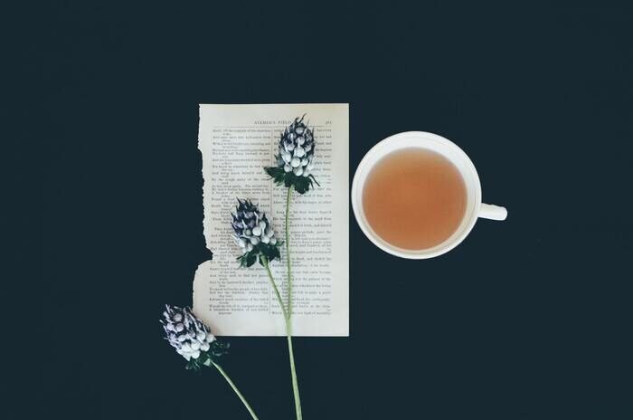 Фотография листа бумаги с цветком и чашкой чая рядом с ним