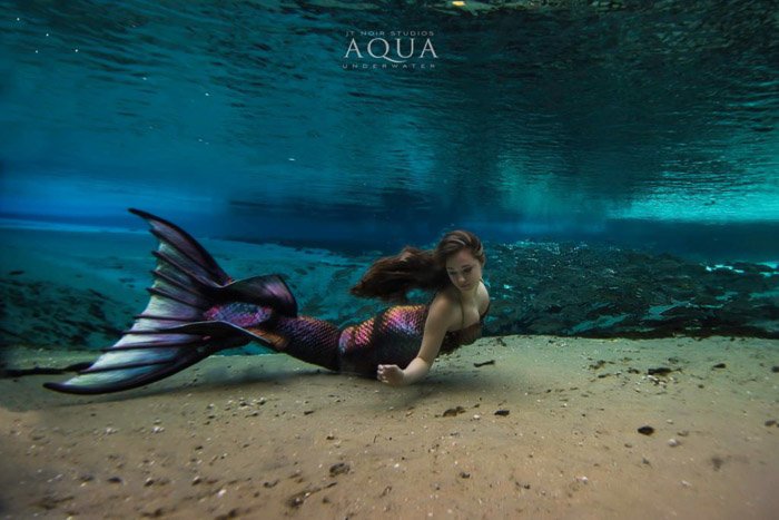 Dreamy underwater portrait of the female model with brightly colored mermaid tail