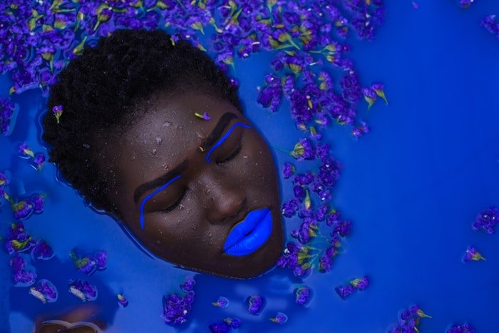 Женское лицо с синим макияжем в синей воде