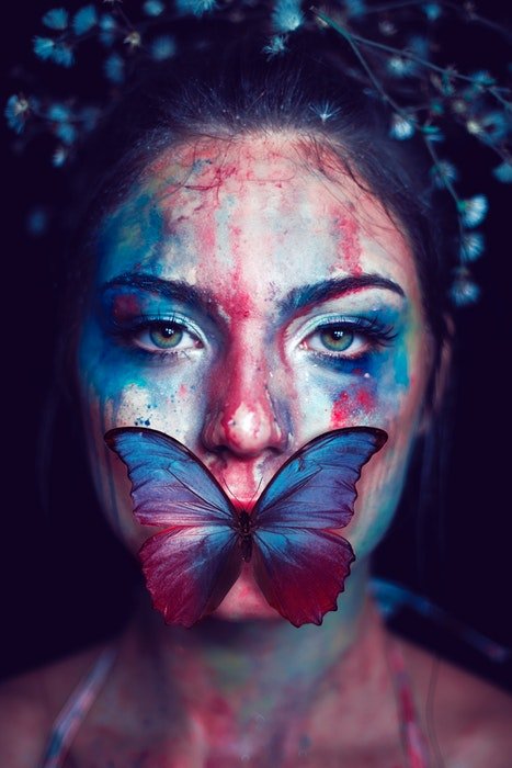 Женщина с нарисованным лицом и бабочкой на губах