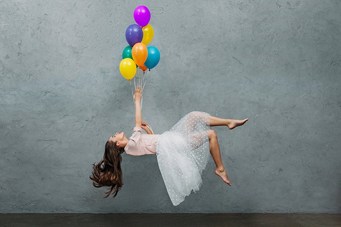 Молодая женщина левитирует с воздушными шарами.