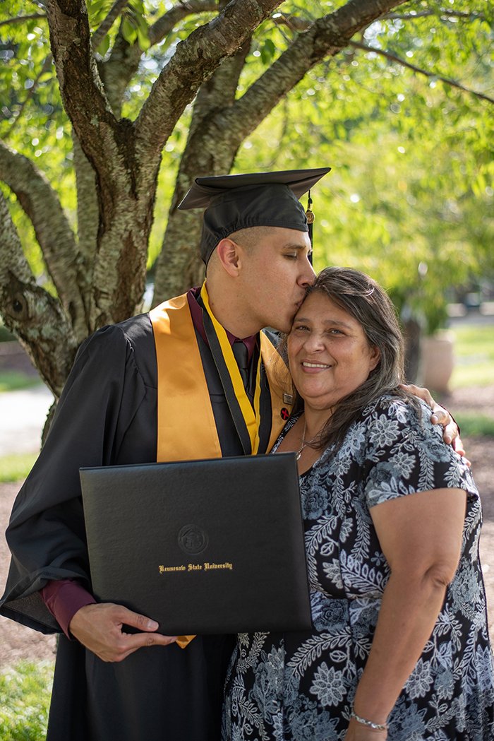 Красивый выпускной портрет мужчины-студента, обнимающего свою мать на улице