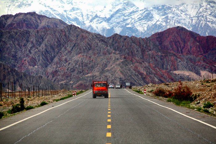 красный грузовик едет по шоссе, красивый горный пейзаж на заднем плане - правило пространства в фотографии