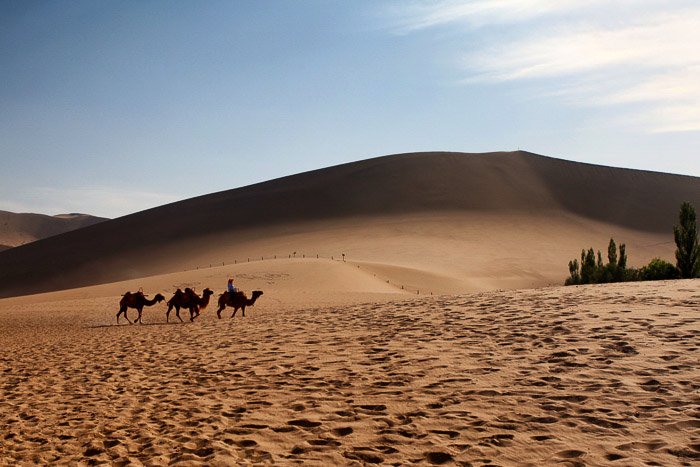 Три погонщика верблюдов движутся по пустынному пейзажу - правило пространства в композиции
